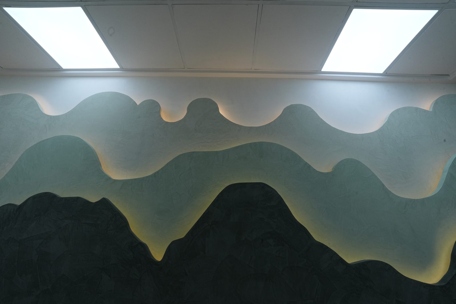 Sculpted teal wave feature wall with cove lighting