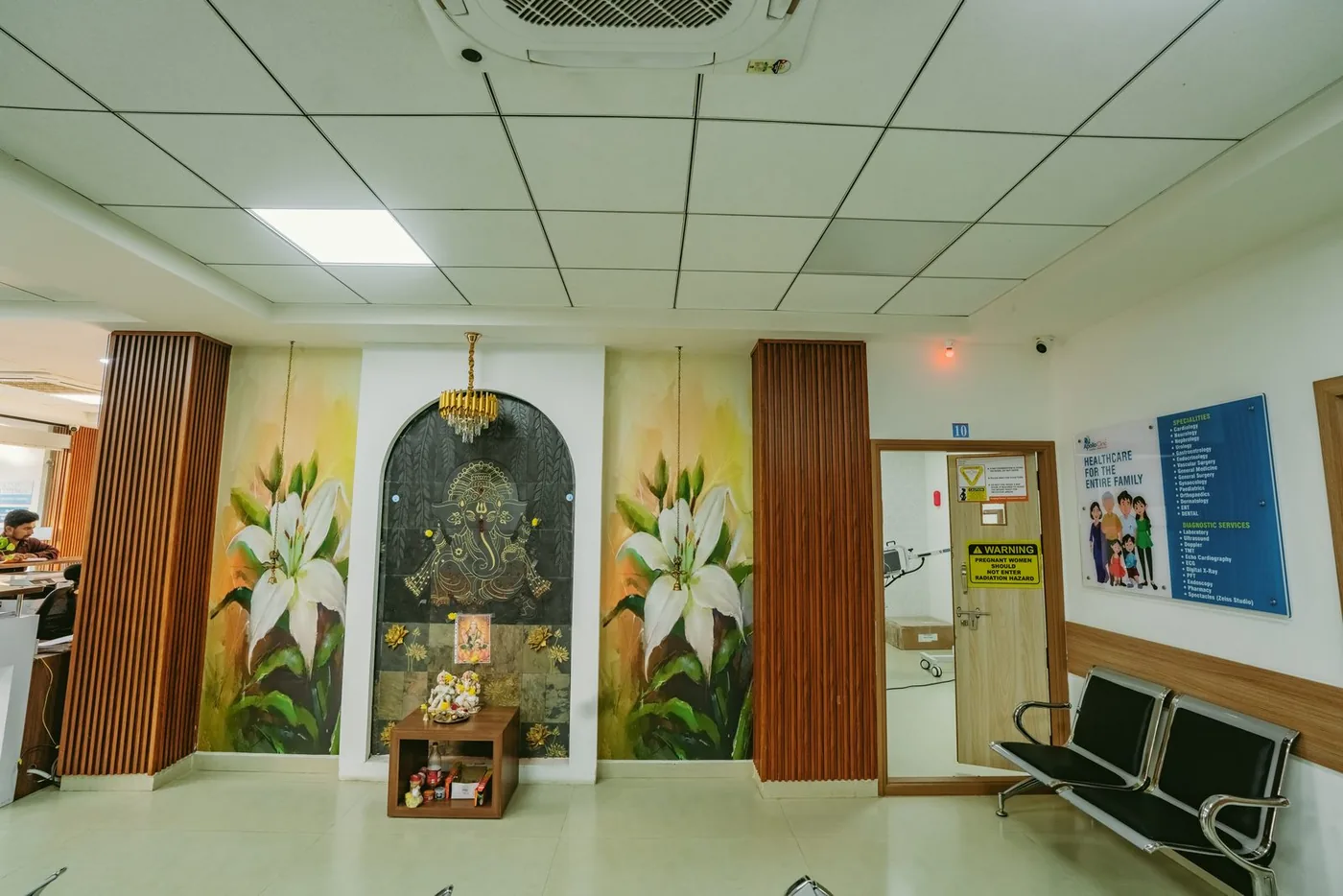 Apollo Akshaya Nagar Waiting Bay — A shrine niche framed by fluted timber panels.