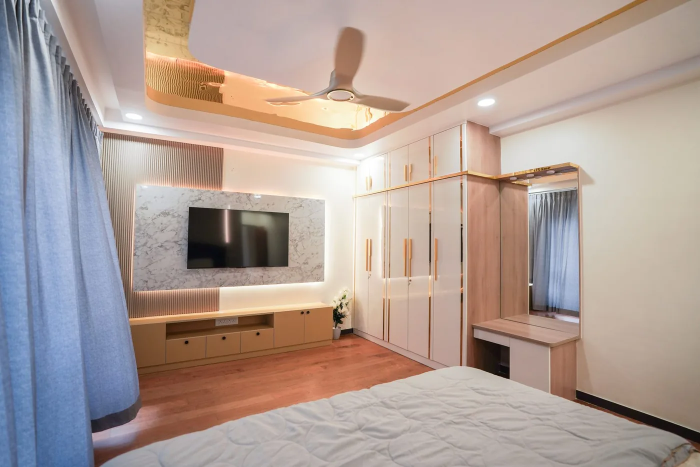 RMZ City View Bedroom Media Wall — A stone-clad media wall built into fitted wardrobes.